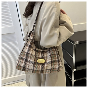 Detail of vintage plaid hobo bag with woolen texture and gold metallic logo plaque