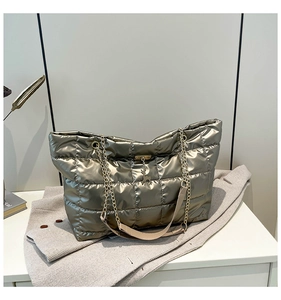Detailed close-up of quilted tote bag with gold chain strap and deer charm accessory
