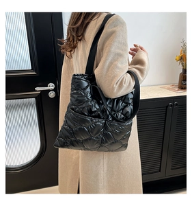 Detailed shot of black quilted tote bag with diamond pattern on shoulder of model