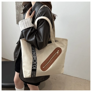 Détail du grand sac cabas en toile crème avec sangles tissées et touches de cuir