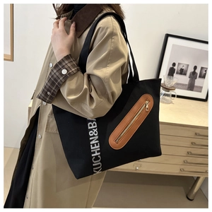 Détail du sac fourre-tout en toile noire avec cuir marron et sangle en ruban lettré