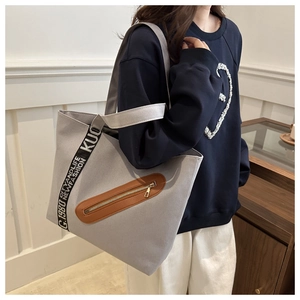 Gros plan du sac fourre-tout gris en toile avec poche en cuir brun et sangle tissée