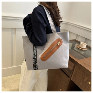 Vue détaillée du sac cabas en toile grise avec ruban décoratif et poche zippée marron