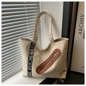 Gros plan du sac fourre-tout en toile avec détail de sangle et écusson en cuir brun