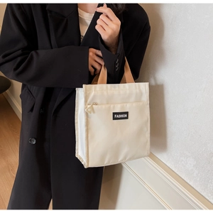 Detail of minimalist beige nylon handbag with exterior zipper pocket and fashion label