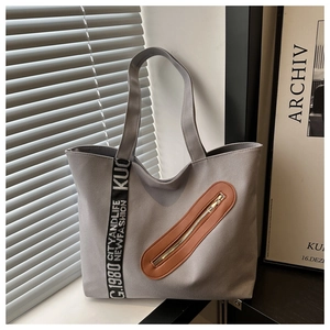 Détail du sac cabas en toile grise avec zip en cuir marron et anses noires griffées