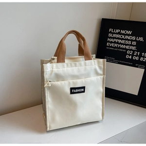 Detail of minimalist canvas tote with thick brown handles and FASHION label on front