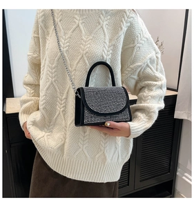 Détail d'un petit sac carré noir orné de strass brillants et d'une bandoulière chaîne