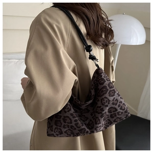 Detail of leopard print tote bag featuring a black shoulder strap with stylish knot design