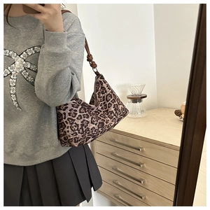 Detail of vintage leopard print crossbody bag with brown knotted faux leather strap