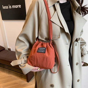 Minimalist orange drawstring bucket bag in lightweight nylon with adjustable shoulder strap