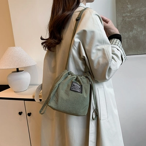 Minimalist green canvas drawstring bucket bag with adjustable shoulder strap for women