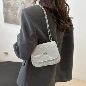 Elegant silver square crossbody bag with metallic butterfly buckle and pleated texture