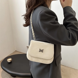 Chic cream leather crossbody bag featuring a silver butterfly clasp and chain strap