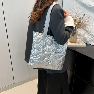Silver quilted tote bag with metallic finish and grey straps shown on a model