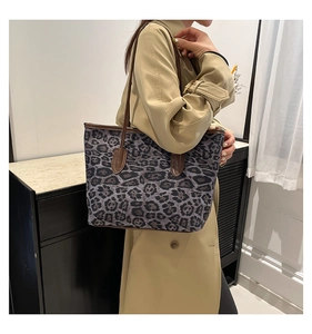 Detail of leopard print tote bag with brown leather handles and canvas texture