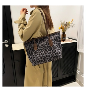 Detailed shoulder view of a large leopard print canvas tote bag with brown leather handles