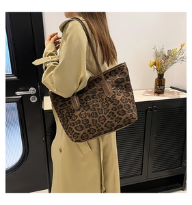 Detail shot of leopard print tote bag with brown leather handles on person in trench coat