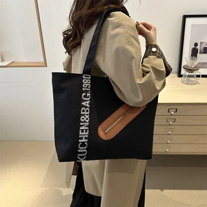 Grand sac cabas en toile noire avec poche en cuir marron et sangle lettrée décorative