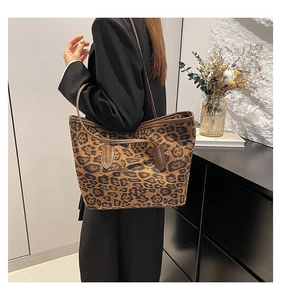 Detail view of large leopard print tote bag with brown straps styled in a modern interior