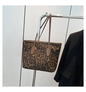 Close-up of leopard print tote bag with brown leather trim hanging on a metal rack