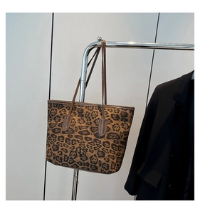 Detail of a large leopard print tote bag with dual straps hanging on a metal display stand
