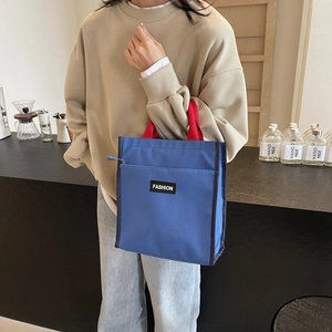 Blue waterproof tote bag with red handles and fashion label for casual office use