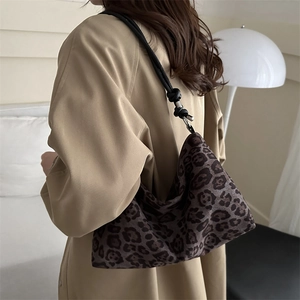 Fashionable leopard print shoulder bag with woven knot strap and minimalist half-moon shape