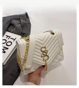 Detail of cream quilted bag with V-shaped stitching and golden S-shaped buckle charm
