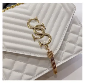 Detail of white quilted leather handbag with gold S-logo and fringe tassel pendant