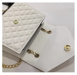 Detail of white quilted handbag showing high-quality gold magnetic buckle and metal chain