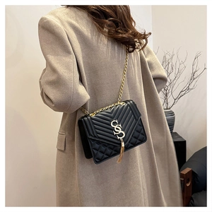 Detail of quilted black leather shoulder bag with gold chain strap and fringe tassel