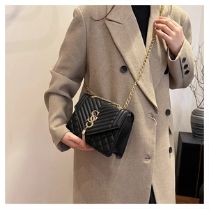 Close-up of black quilted leather shoulder bag with gold metal tassel and chain strap