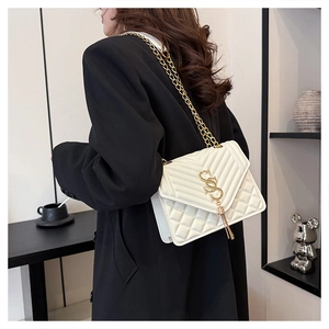 Close-up of white quilted crossbody bag with gold chain and stylish tassel detail