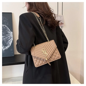 Detail of khaki quilted crossbody bag with golden chain strap and tassel charm
