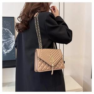 Detail of tan quilted handbag with gold chain strap and metal tassel on black coat