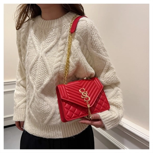 Close-up of red quilted leather handbag with gold chain strap and tassel detail