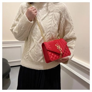 Detail of red quilted leather crossbody bag with gold S-logo and chain strap on model