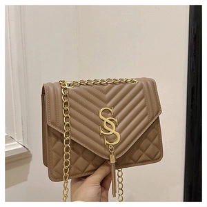 Close-up of brown crossbody bag with V-shaped quilting, gold fringe, and chain strap
