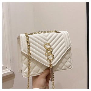 Close-up of white quilted leather bag with gold fringe logo and elegant chain strap