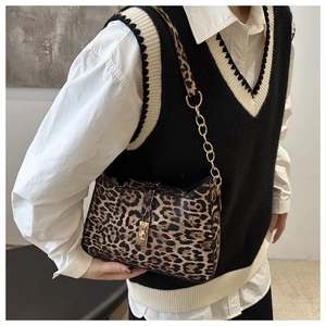 Detail of leopard print crescent bag with gold chain strap worn with a stylish outfit
