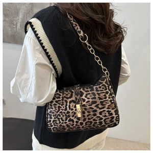 Detail shot of leopard print crescent bag with gold chain strap on model's shoulder