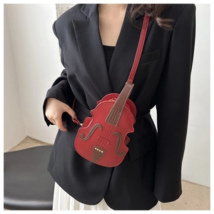 Detailed side view of a creative red violin-shaped crossbody bag worn by a model
