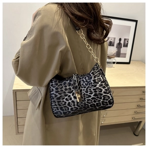 Detail of leopard print shoulder bag with gold chain strap and metallic clasp on model