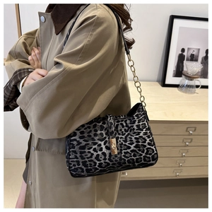Detail of leopard print underarm bag featuring golden metal clasp and chain strap