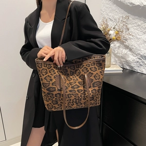 Chic leopard print large tote bag with leather handles shown in a lifestyle street setting