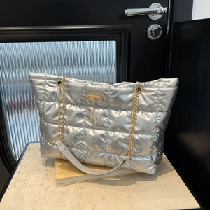 Quilted silver tote bag with golden chain and deer pendant on a stylish background
