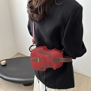 Unique violin shaped red leather crossbody bag with brown accents and gold hardware strap