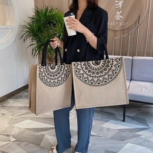 Linen tote bag set with black mandala patterns and woven handles shown in a cafe