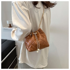 Close-up of brown quilted bucket bag with gold chain strap and pearl drawstring detail